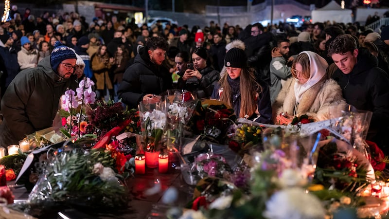 People lay flowers and light candles for the victims of the fire at the "Le Constellation" bar...