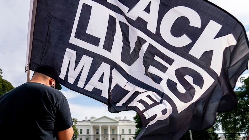 FILE - A man carries a Black Lives Matter flag in Lafayette Square outside the White House on...